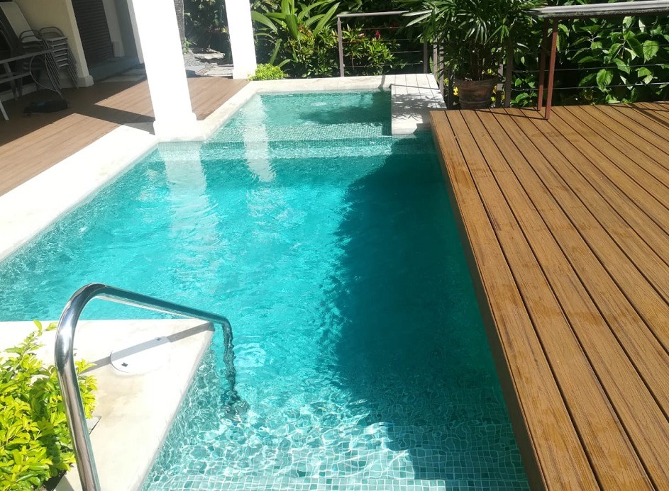 beautiful pool construction, with green spanish tiling, and wooden decking